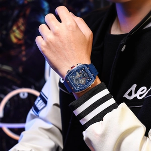 Close-up of a blue rubber strap and rose gold barrel-shaped watch dial on a wrist