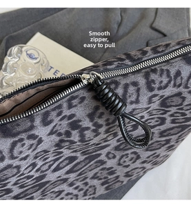 Detail of a smooth silver zipper with black leather pull on a leopard print tote bag