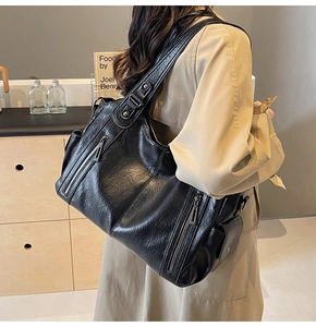 Close-up of black lychee-textured leather tote bag with functional side zipper pockets