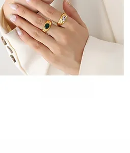 Detailed close-up of retro gold-plated rings with green zircon and white stone on a model