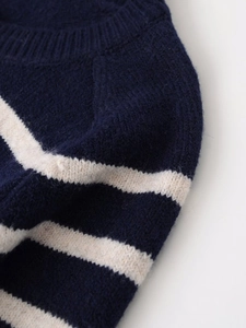 Detail of ribbed crew neck and navy striped knit texture on thick wool blend sweater