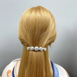 Silver metallic hair clip with irregular texture on a model's hair, professional back view