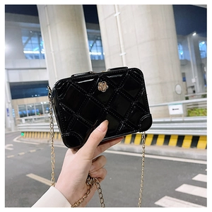 Detail of black PVC jelly bag with quilted pattern, gold chain and camellia flower ornament