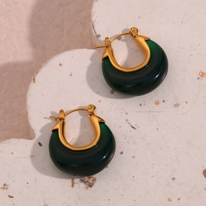 Close-up of green resin crescent hoop earrings with gold-plated metal clasp on stone base