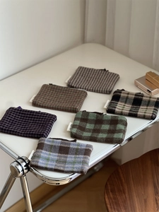Flat lay of multiple colorful plaid tweed storage pouches with simple wish woven labels