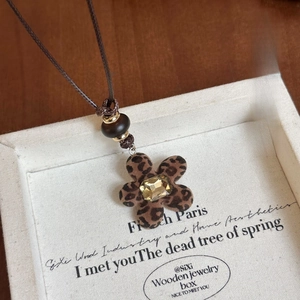 Detail of leopard print flower pendant with champagne crystal and wooden bead necklace