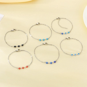 Detail of six stainless steel evil eye bracelets in various colors on beige fabric