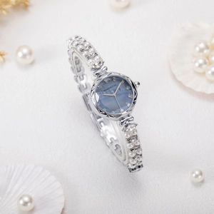 Elegant silver bracelet watch for women featuring white pearls and a blue sunray dial