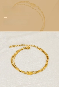 Detailed view of gold double-layer chain bracelet with Hamsa palm charm and lobster clasp