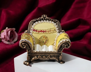 Detail of vintage sofa-shaped jewelry box with yellow fabric and bronze engraved frame