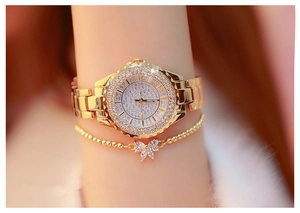 Macro shot of gold-tone women's watch with rhinestones and matching bow bracelet on wrist