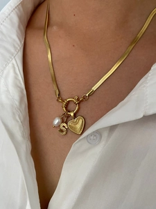 Detail of golden snake chain necklace with pearl, letter S and heart charms