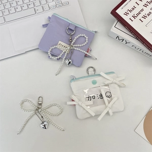 Detail of nylon card holder bag with pearl bow pendant and heart-shaped metal charm