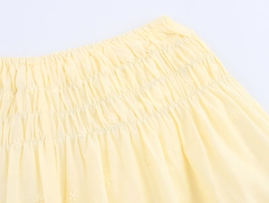 Detail of yellow smocked fabric with delicate floral embroidery and elastic texture