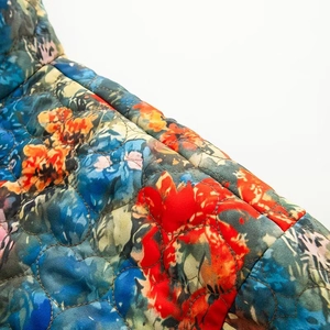 Detail of quilted cotton fabric with colorful floral embroidery and geometric stitching