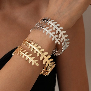 Detailed view of leaf pattern metal arm cuff with gold and silver metallic finishes