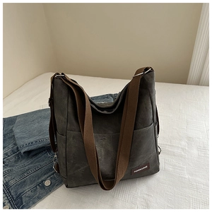 Detail view of large dark grey canvas tote bag with brown fabric strap and fashion label