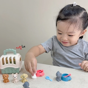Girl playing with pet care toy set including dog carriers, puppies and feeding bowls