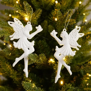 Two white glitter Christmas angel ornaments hanging on a tree with a warm bokeh background