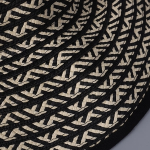 Macro detail of sun hat showing black and white chevron straw weave with spiral stitching