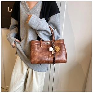 Détail d'un sac cabas en cuir marron vintage avec fermoir métallique et breloques