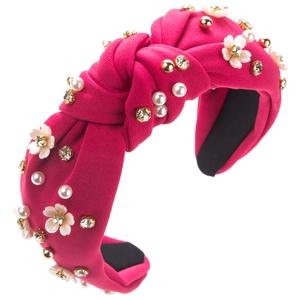 Détail du serre-tête noué rose fuchsia avec fleurs en résine blanche et ornements en perles