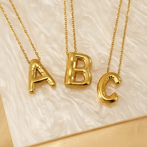 Colliers lettres initiales 3D gonflées plaqués or 18 carats A B C sur fond ondulé blanc