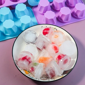 Macro view of silicone mold with crystal clear fruit ice cubes in a white ceramic bowl
