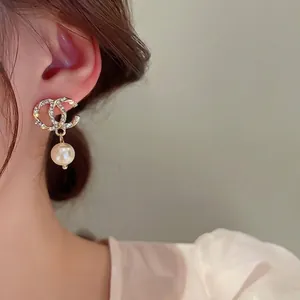 Elegant gold CC logo earrings with sparkling crystals and a white pearl drop pendant