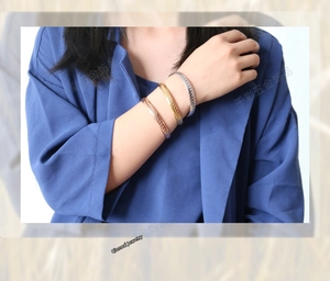 Close-up of three-tone wheat pattern stainless steel bangles worn by a model