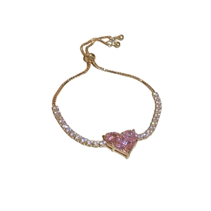 Adjustable gold heart bracelet with pink gemstone and zircon stones on white background