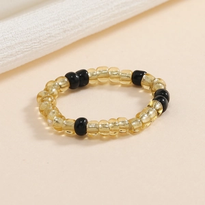 Dettaglio macro di anelli elastici con perline ambra e nere su uno sfondo beige neutro