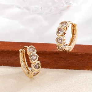 Golden heart-shaped hoop earrings with zircon pavé setting on a textured surface