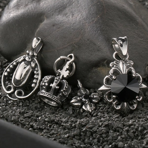 Macro shot of vintage silver-tone crown and cross pendants on dark textured rocks