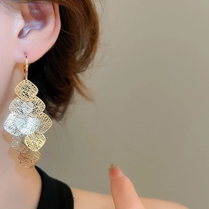 Close-up of geometric diamond-shaped mesh tassel earrings in gold and silver finish