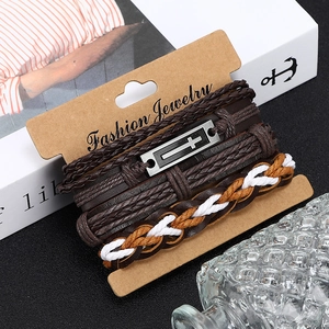 Gros plan d'un bracelet multicouche en cuir marron avec un charme de croix argentée antique