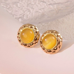 Detailed close-up of vintage gold button earrings with yellow gem and quilted texture