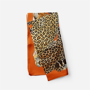 Detail of orange silk scarf showing artistic cheetah illustration and fine hem stitching