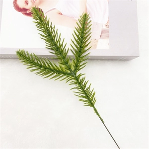Detailed view of dark green artificial pine needle branch on a soft white texture