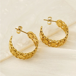 Detailed close-up of gold hollow C-shaped earrings with vintage floral cutout patterns