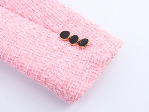 Detail eines rosa Tweed-Jackenärmels mit Textur und drei schwarz-goldenen Knöpfen
