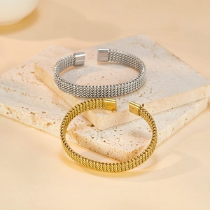 Close-up of gold and silver woven stainless steel mesh open bangles on stone
