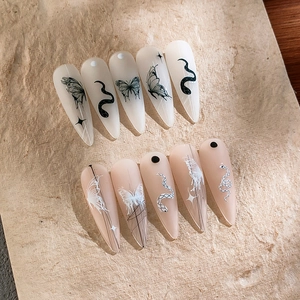 Faux ongles stiletto longs mats avec motifs papillon et serpent sur fond de pierre