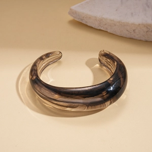 Detailed view of wide open resin bangle with amber tortoise shell pattern on stone