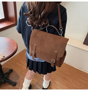 Bolso mensajero vintage marrón con hebillas decorativas usado por modelo en interiores