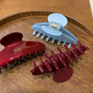 Close-up of three glossy resin hair claws in burgundy and blue with gold lettering