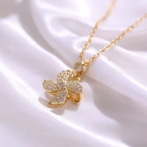 Macro detail of gold windmill pendant necklace with sparkling micro-pave crystals on silk
