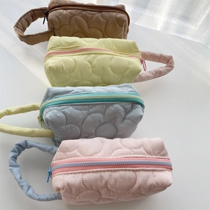 Detailed view of quilted flower patterned cosmetic bags in brown, yellow, blue, and pink