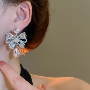 Close-up of bow knot teardrop earring with silver needle and pavé crystal rhinestones