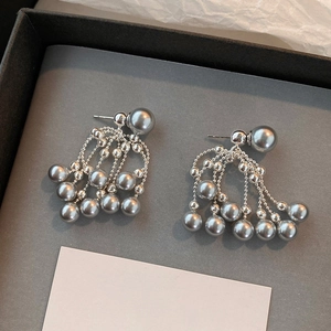 Detail of silver-tone tassel earrings with grey pearls on elegant jewelry display